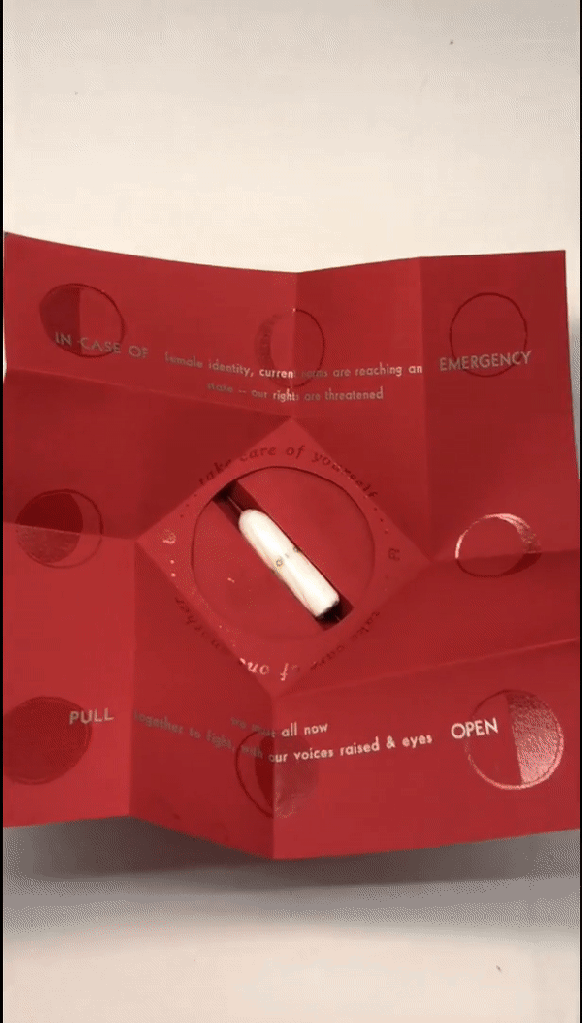 Looped short video showing the gift box unfolded and open - a hand reaches into view to remove the applicator-free tampon which is tucked into the box - camera moves closer to show the vulva-shaped interior of the box